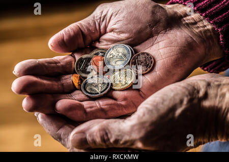 Titolare di pensione o di rendita uomo tenendo in mano delle monete in euro. Il tema delle pensioni basse Foto Stock