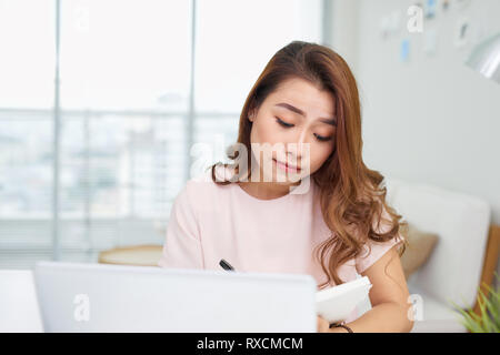 Perplesso confuso donna asiatica di pensare il disco interessato circa online soluzione problema guardando lo schermo del notebook, preoccupato grave Asian imprenditrice focus Foto Stock