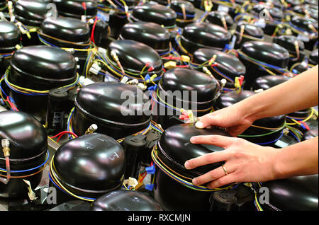 Lavoratore prendendo un compressore frigorifero con le mani Foto Stock