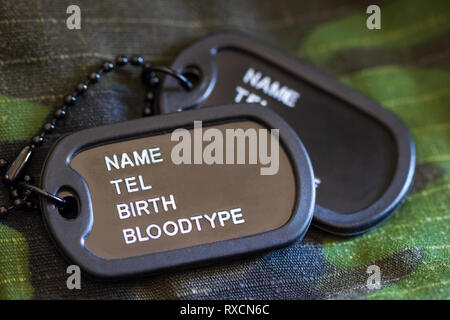 Tag soldato o dog tag prevista sul mantello militare e la luce del sole di mattina. Concetto di protezione per un nuovo giorno. Foto Stock