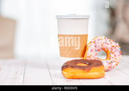 Tazza di caffè e cioccolato ciambella sulla tavola di legno. Pausa caffè con ciambelle. Foto Stock