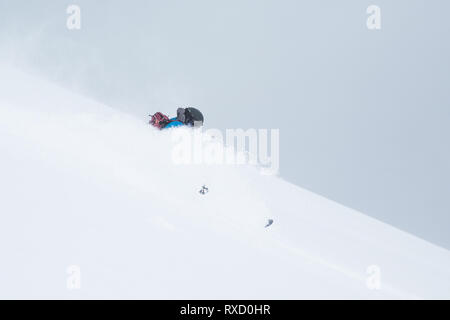 Backcountry rider in blu con zaino passando attraverso la neve profonda di Hokkaido in Giappone. Foto Stock