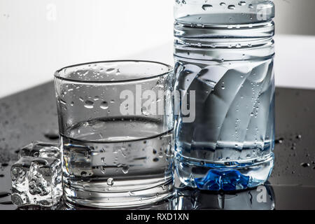 Sudati refrigerate acqua in bottiglia, i cubetti di ghiaccio e vetro Foto Stock