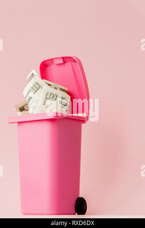 Di dollari di banconote in rosa spazzatura su sfondo rosa. Foto Stock