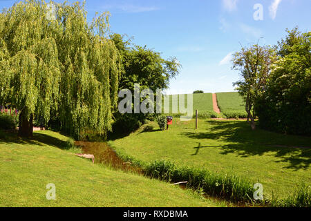 Piuttosto la ricreazione massa / parco con un flusso in esecuzione attraverso di esso, sulla egde di Lavenham cittadina nel Suffolk, Regno Unito. Giornata di sole. Foto Stock