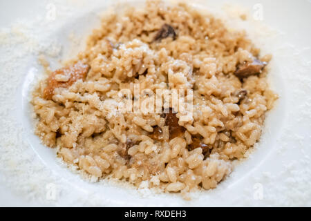 Cucina Italiana - risotto con funghi porcini (riso bollito con funghi porcini) sulla piastra bianca in un ristorante locale in Lombardia Foto Stock