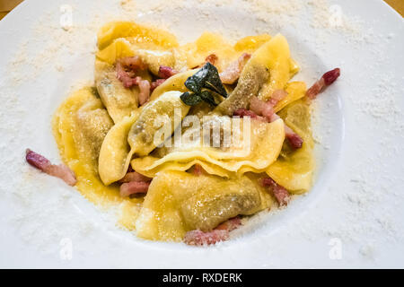 Cucina Italiana - casoncelli alla bergamasca (Pasta farcita con briciole di pane, uova, parmigiano, carne di manzo macinata, salame) sulla piastra bianca in un ristorante locale Foto Stock