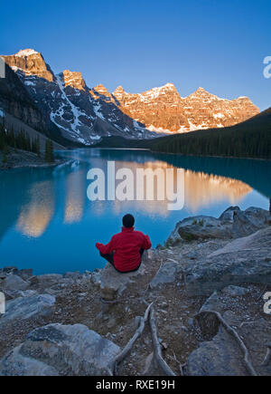 Metà maschio età meditando la mattina presto a Moraine Lake, il Parco Nazionale di Banff, Alberta, Canada Foto Stock