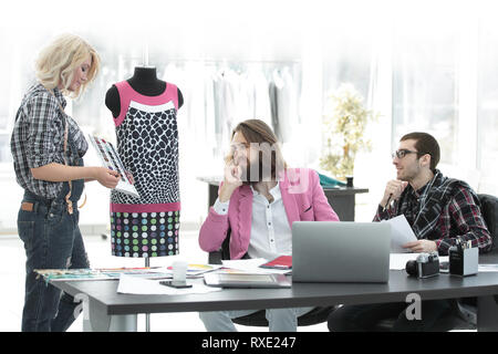 Gruppo di disegnatori di moda, durante la creazione di una promettente collezione di abbigliamento in un moderno studio Foto Stock