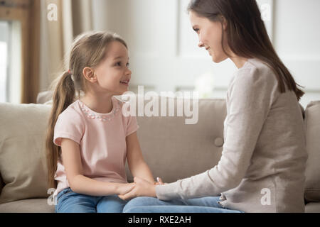 Amare la madre e il bambino per mano di parlare seduto sul divano Foto Stock