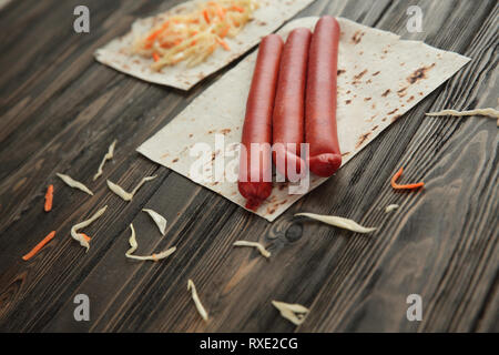 Salsicce affumicate, cavolo e pane pita isolato su sfondo di legno Foto Stock