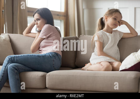 Testardo la madre e il bambino ragazza seduta si voltò sul divano Foto Stock
