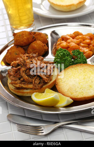 North Carolina piastra barbecue ; tirata di maiale, frittelle di farina di mais, fagioli al forno e coleslaw Foto Stock