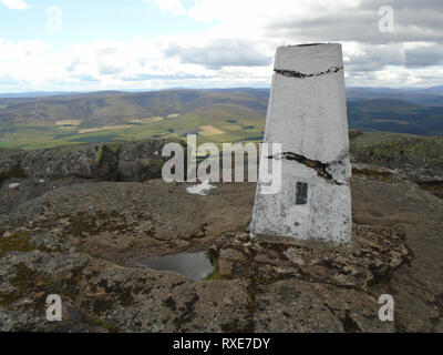 Il Concreate Trig colonna sulle rocce al vertice della montagna scozzese Corbett Ben Rinnes in Cairngorm National Park, Scotland, Regno Unito. Foto Stock