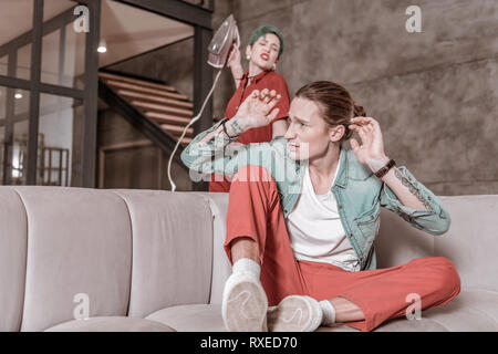 Con capelli verdi donna tenendo il ferro sollevando la mano contro il suo uomo Foto Stock