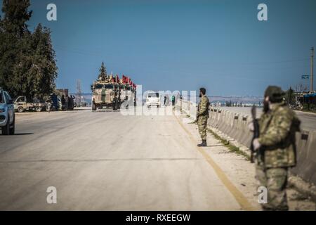Soldati armati visto la guardia ai lati della strada durante la pattuglia. L'esercito turco inizia il suo primo patrol intorno alla frontiera siriana nella zona demilitarizzata tra i punti di controllo con un numero di veicoli blindati. Foto Stock