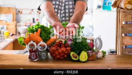 Vegetariani e cibo sano stile di vita a home concetto - tavolo in cucina piena di miste di verdure colorate e man mano che vi mostra la freschezza Foto Stock