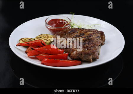 Spiedini di carne su un piatto con verdure grigliate, zucchine e bulgaro pepe rosso, decorate in verde e salsa Foto Stock