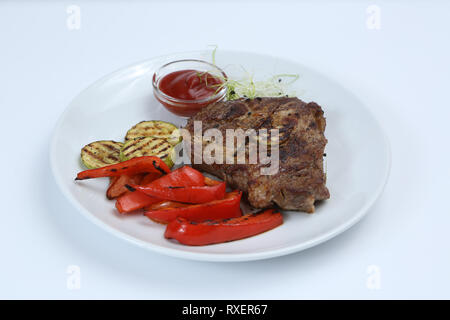 Spiedini di carne su un piatto con verdure grigliate, zucchine e bulgaro pepe rosso, decorate in verde e salsa Foto Stock