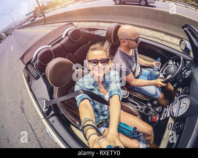 Coppia felice guida auto aperta e rendendo selfie, luna di miele Vacanza in auto convertibili, compagni d'anima godendo road trip, godendo di estate Foto Stock