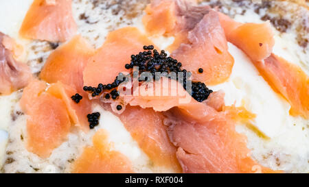 Crepes con formaggio morbido e fette di salmone decorate con artificiali di caviale nero da vicino in un ristorante locale in Lombardia Foto Stock