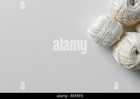 Beige e bianco hanks per un crochet su un tavolo bianco sfondo con copia spazio. Foto Stock