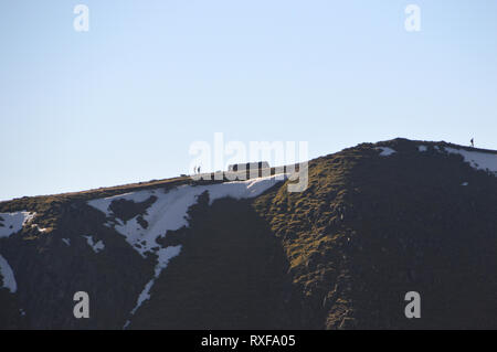 Tre gli escursionisti e un cane a camminare sul vertice del Wainwright Helvellyn in inverno nel Parco Nazionale del Distretto dei Laghi, Cumbria, Inghilterra, Regno Unito. Foto Stock