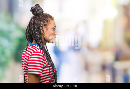 Giovani capelli intrecciati African American Girl su sfondo isolato guardando al lato, profilo relax posano con faccia naturale con sorriso sicuro. Foto Stock