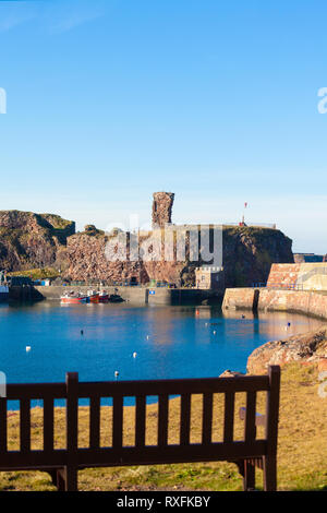 Dunbar Harbour e Dunbar Castello con una panchina nel parco in primo piano. Sfondo. Dunbar, East Lothian, Scozia Foto Stock