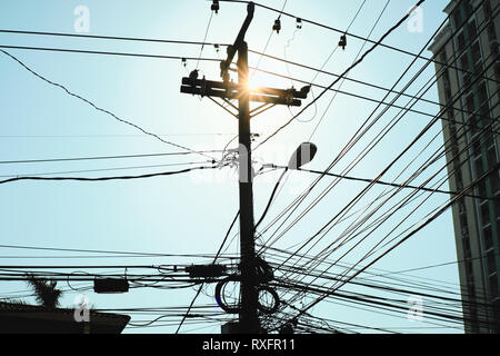 Basso angolo vista di calcestruzzo per post street lampada e fili elettrici al crepuscolo. Fitta rete di cavi in silhouette appeso su un palo in Panama City. Co Foto Stock