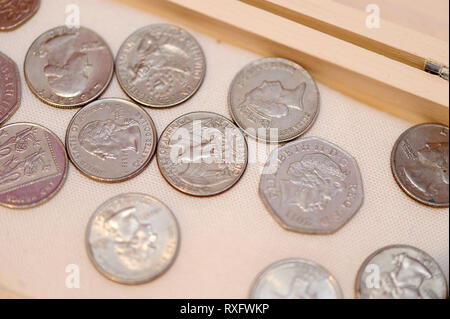 Monete d'argento in cassa di legno con tessuto bianco sullo sfondo Foto Stock