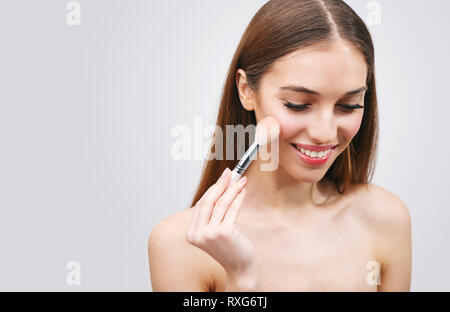 Una giovane donna di liquido applicato foundation sul suo viso con una spazzola Foto Stock