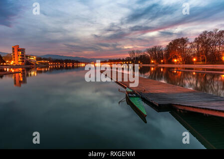 Tramonto sul canale di canottaggio nella città di Plovdiv - Capitale europea della cultura 2019, la Bulgaria, l'Europa. Pier con la barca di fronte. Foto Stock