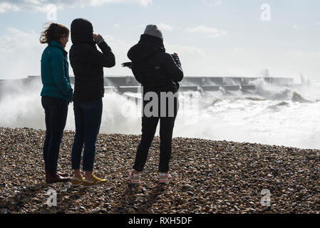 Brighton, East Sussex, Regno Unito. Il 10 marzo 2019. Regno Unito Meteo. Venti forti fino a 50mph sono che si traducono in enormi onde si infrangono sul lungomare di Brighton come spettatori guarda sulla. Il Met Office ha rilasciato un giallo di avvertimento meteo come venti più forti sono previste in aumento durante la settimana. Credito: Francesca Moore/Alamy Live News Foto Stock