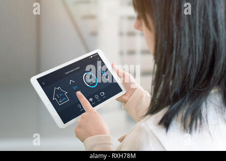 Donna di controllo di temperatura nella stanza vivente con smart home control app sui tablet. Vista dalla spalla. Tehnology concetto di automazione. Foto Stock