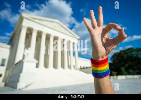 Mano che indossa il Gay Pride rainbow con la fascetta da polso rendendo okay gesto al di fuori della Corte suprema di Washington, DC, Stati Uniti d'America Foto Stock