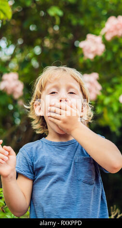 Ragazzo soffia il naso di fronte ad albero in fiore. Molla il concetto di allergia. Bambini le allergie del formato verticale per Instagram storia mobile o storie dimensioni Foto Stock