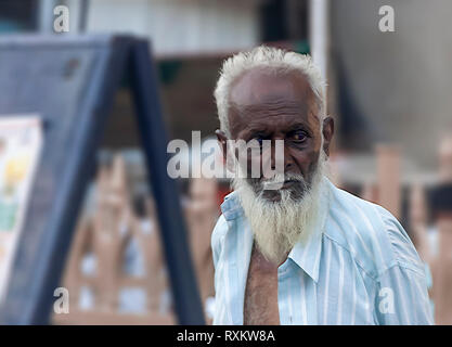 Un uomo musulmano che ha la sua maglietta aperto a raffreddare se stesso a caldo in estate meteo guardando qualcosa nel lontano. Hyderabad, Telangana, India. Foto Stock