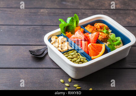 Cibo sano e scatola di pranzo. Pasto sano prep contenitori con polpette di fagioli, pasta, verdure, frutti di bosco, semi e noci in un contenitore su un backgro scuro Foto Stock