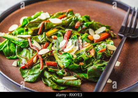 Barbabietole da insalata verde con i dadi nella piastra di nero, sfondo bianco. Sano cibo vegan concetto. Foto Stock