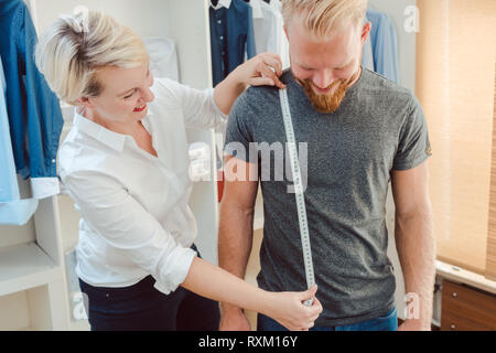 Adattare la misura il cliente con nastro di misurazione Foto Stock