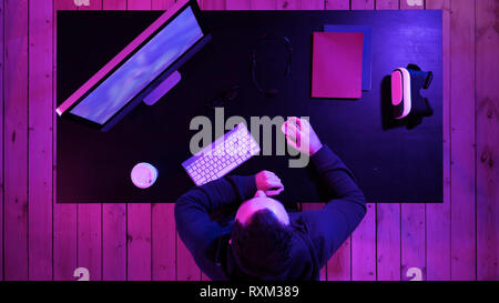 Gioiosa gamer guy riproduzione di video giochi sul computer e che mostra il pollice fino alla telecamera. Foto Stock