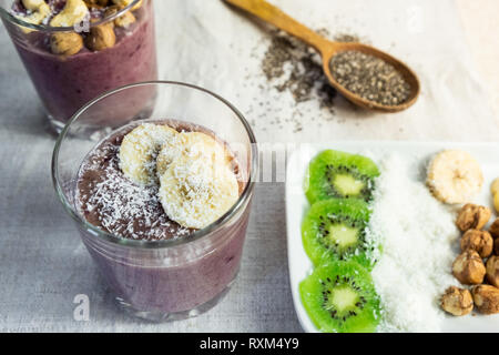Ciotola Smoothie colazione e ingredienti di farcitura. Organico sano cibo crudo pasti in naturale sfondo rustico Foto Stock