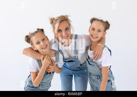 Persone, la famiglia e i bambini concetto - Ritratto di una bella madre che abbraccia il suo figlie gemelle su sfondo bianco Foto Stock