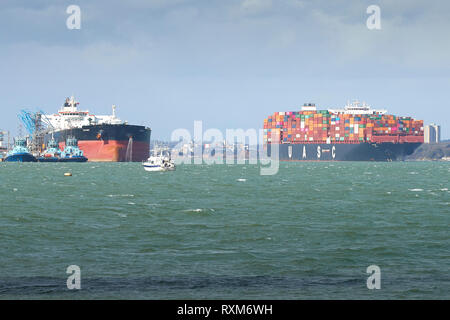 La UASC Ultra-Large nave portacontainer, SAJIR, uscire il Southampton Container Terminal, passa il Fawley raffineria di petrolio, Hampshire, Regno Unito. Foto Stock