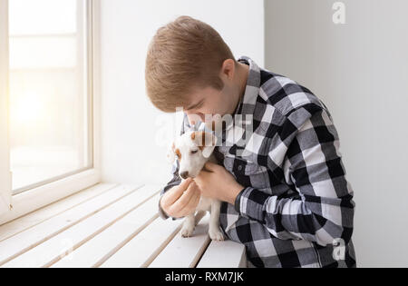 Le persone e il concetto di pet - uomo felice tiene un cane Jack Russell Terrier oltre lo sfondo della finestra Foto Stock