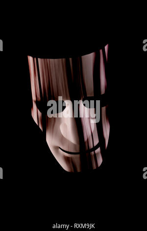 Scary maschera facciale con capelli appesa sopra la faccia. Nero scuro dello sfondo. Halloween o orrore o metropolitana il concetto di criminalità Foto Stock