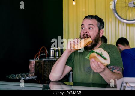 L'uomo affamato che mangia un panino Foto Stock