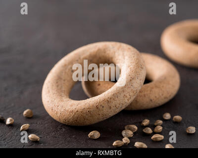 A forma di anello cracknel con grano intero di semi di canapa e di farina di semi di canapa su sfondo nero. a forma di anello cracknel close up. Spazio di copia Foto Stock