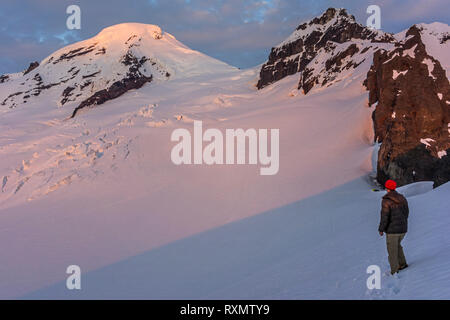 Un maschio di scalatore godersi il tramonto sul Monte Baker, Washington, Stati Uniti d'America Foto Stock